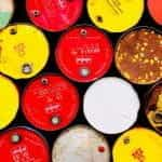 A colorful closeup of red, yellow, white, and brown barrels containing oil.