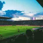 A football game in a large stadium as seen from the crowd.