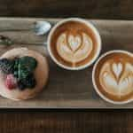 A puff pastry and two coffee mugs placed on a wooden serving tray.