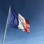 The French flag flying against a blue sky.