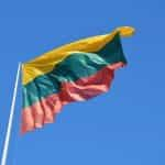 The flag of Lithuania against a blue sky.