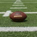 A classic American football sitting on an outdoor football pitch at the start of a game.