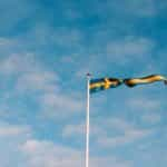 A blue and yellow flag against a blue sky.